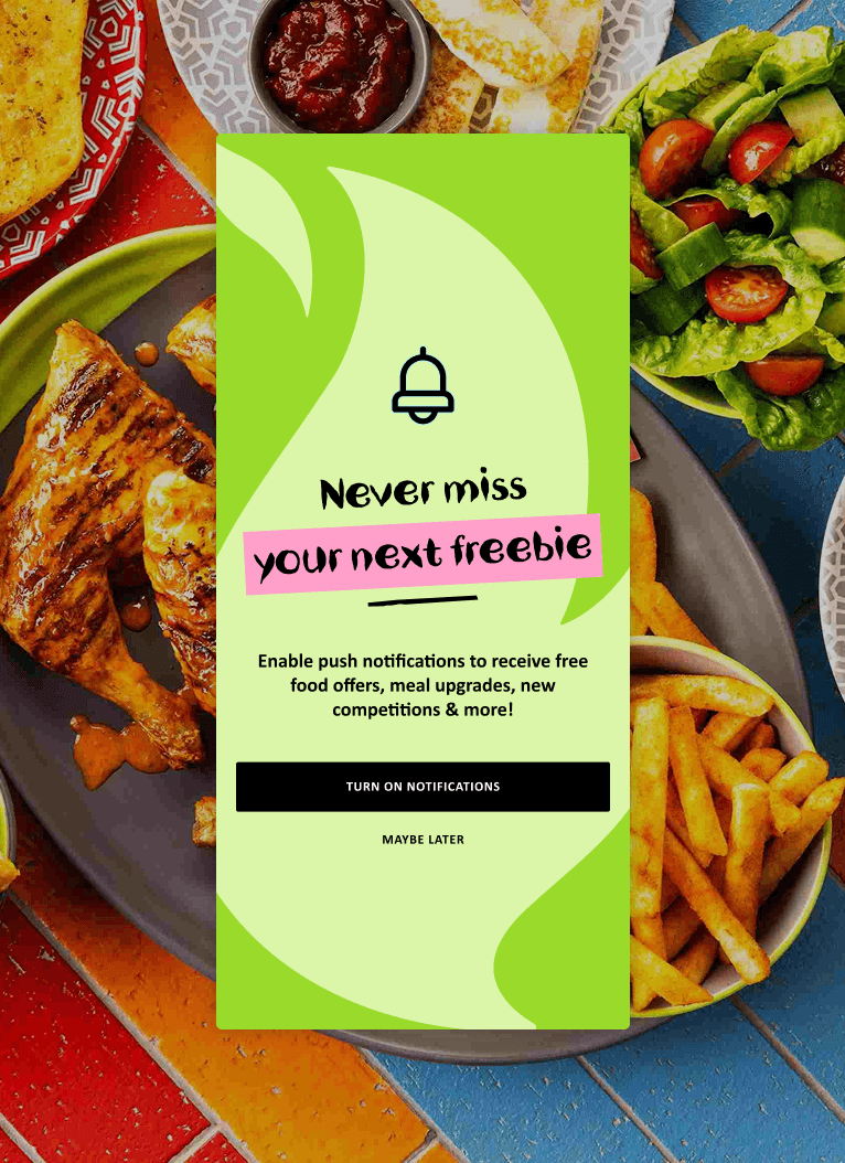 Notification pop-up on a food website, encouraging users to turn on push notifications to receive offers, meal upgrades and freebies. Background features plates of grilled chicken, fries, salad and bread.